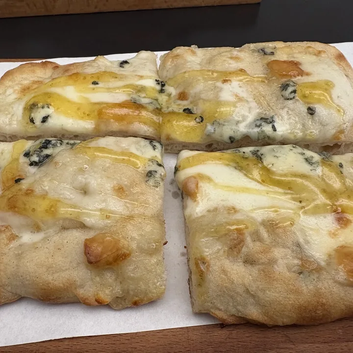 Teglia bianca con formaggio erborinato fuso e un filo di miele.