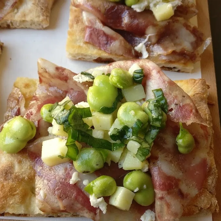 Teglia con salume, cubetti di formaggio fresco e verdure verdi.